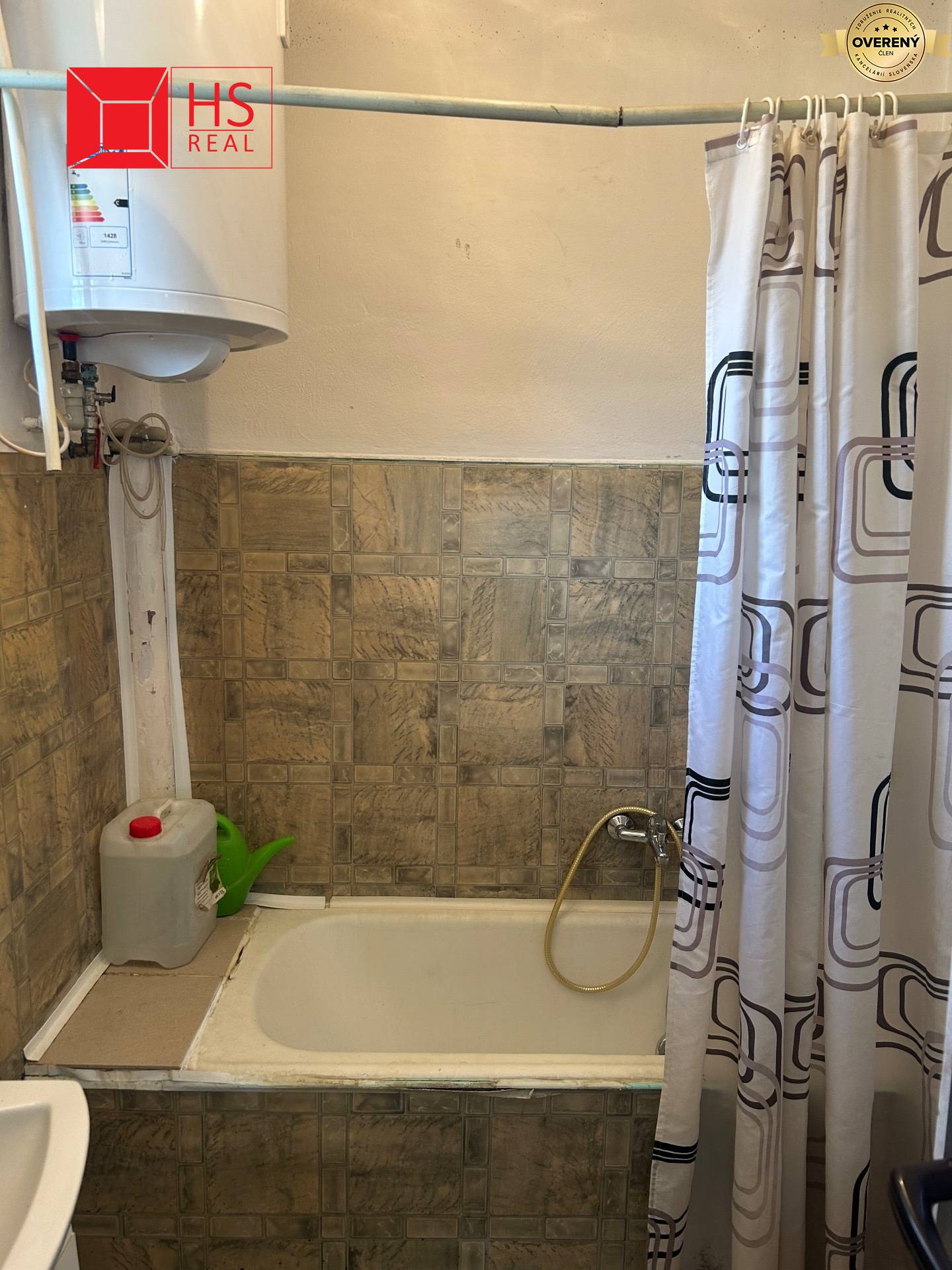 Kúpeľňa rodinného domu s vaňou, sprchovacím závesom a bojlerom nad obkladom.