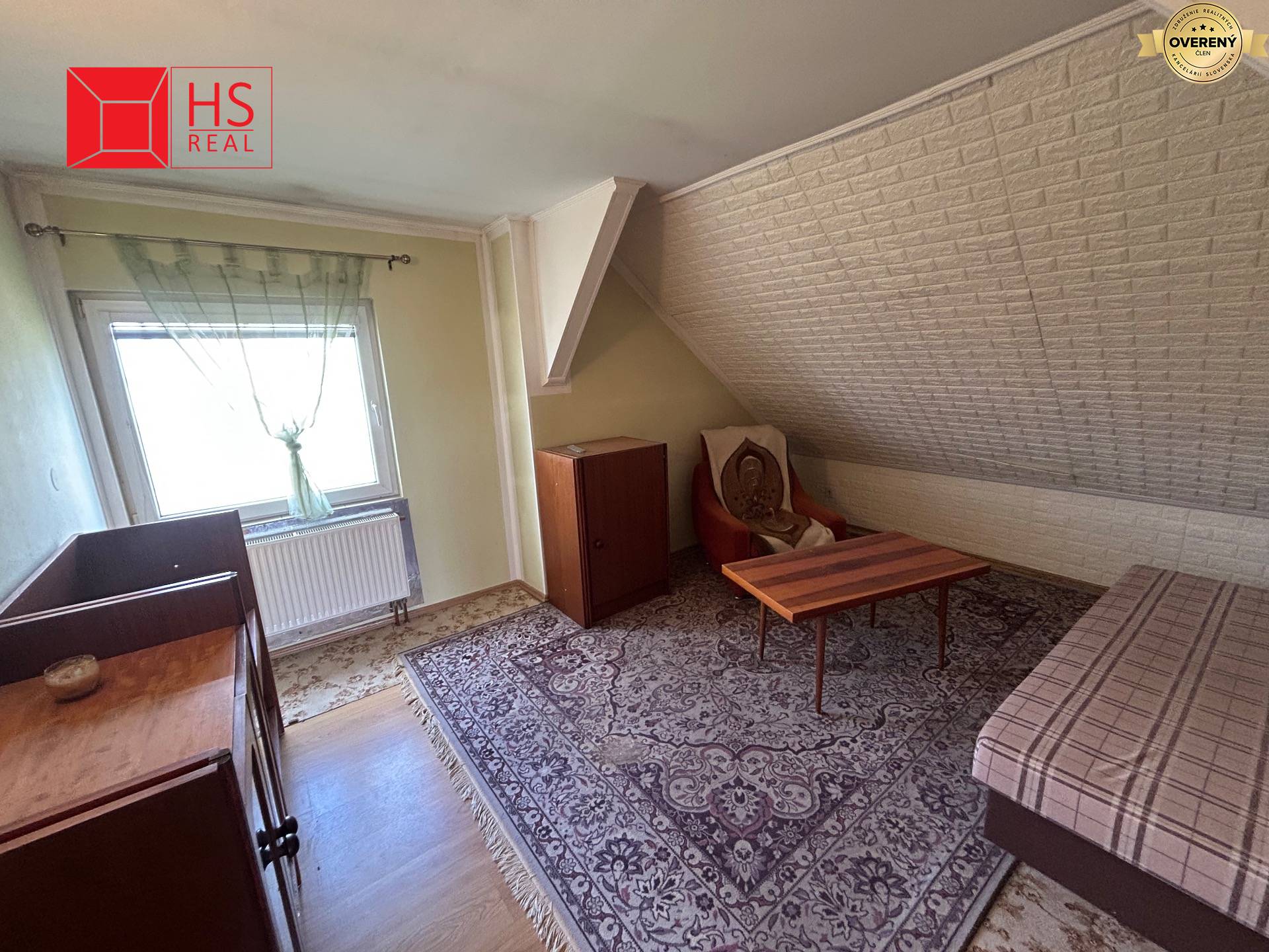 Miestnosť v rodinnom dome s kobercami, stolíkom a podlahou s dreveným dekorom.