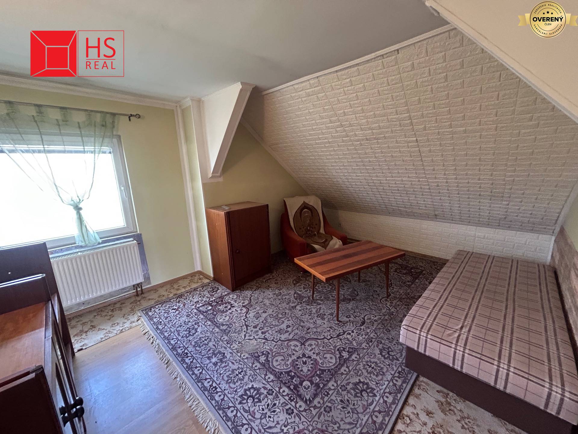 Izba v rodinnom dome s pohovkou, kobercom a stolom na podlahe s dreveným dekorom.