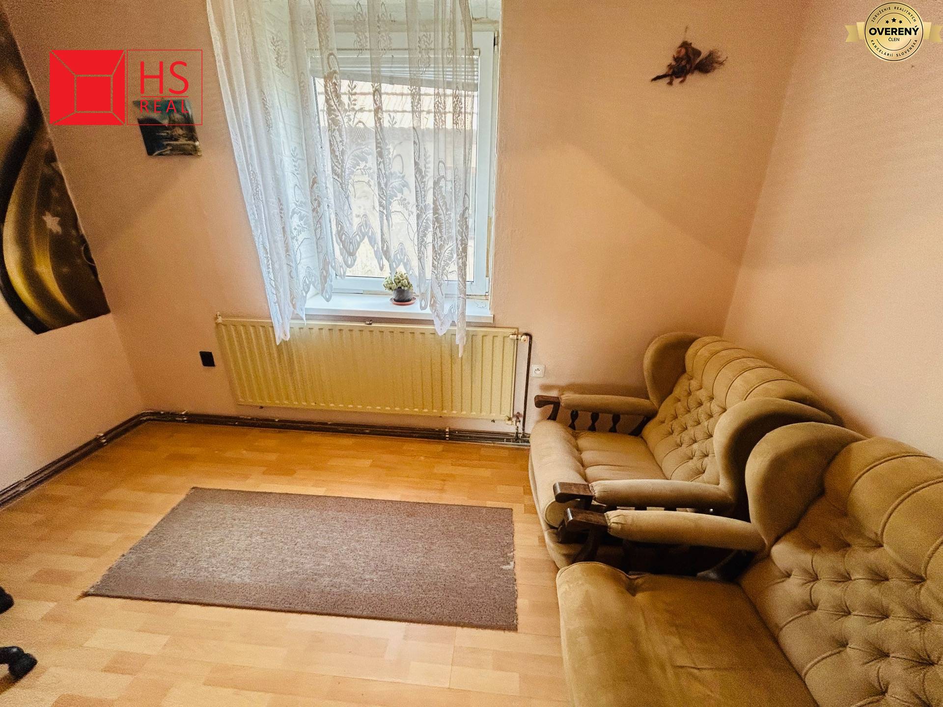 Izba v rodinnom dome s pohovkami, závesmi a podlahou s dreveným dekorom.