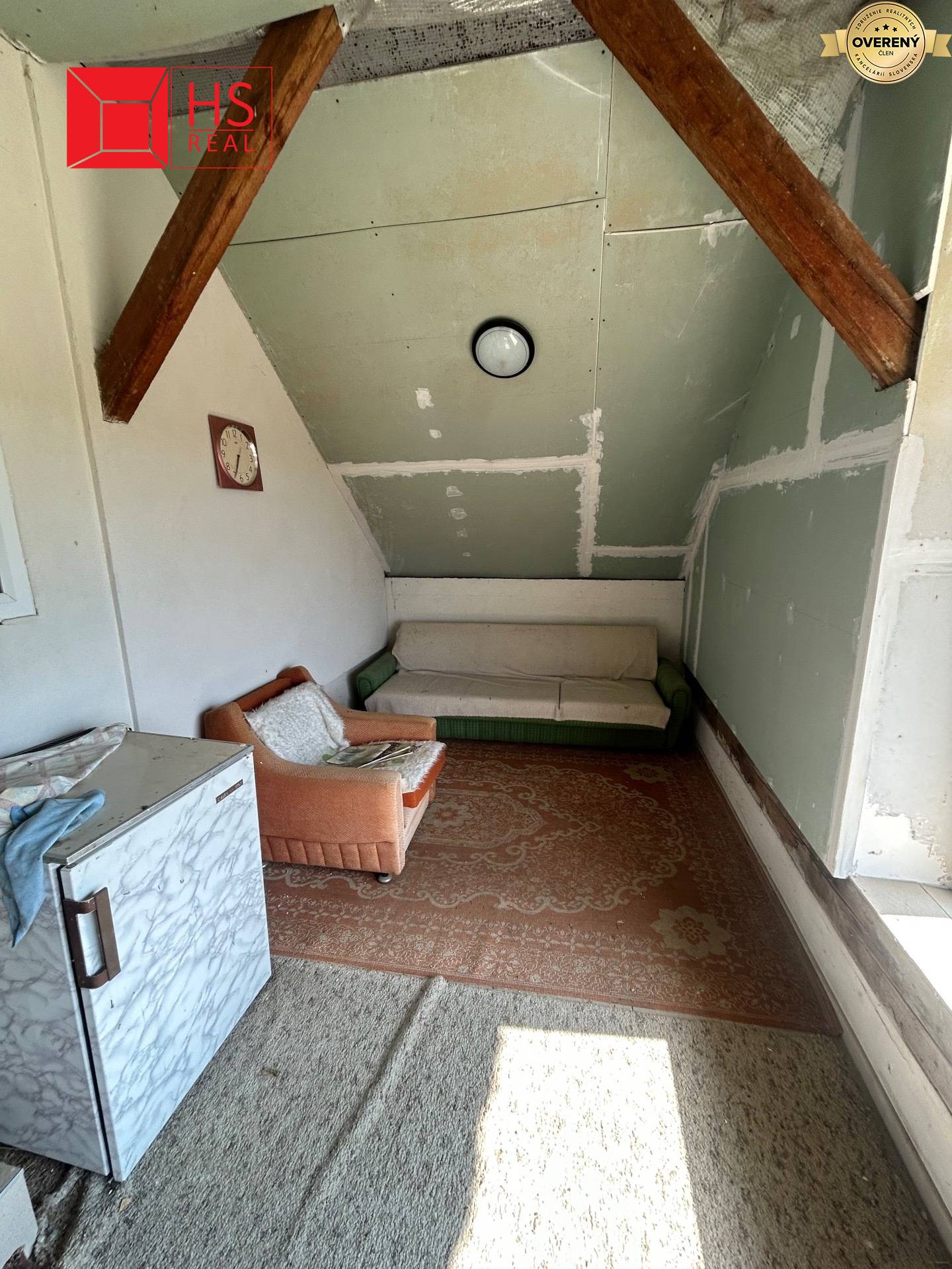 Obývacia izba v rodinnom dome s kobercami, sedačkou a starožitným kreslom.