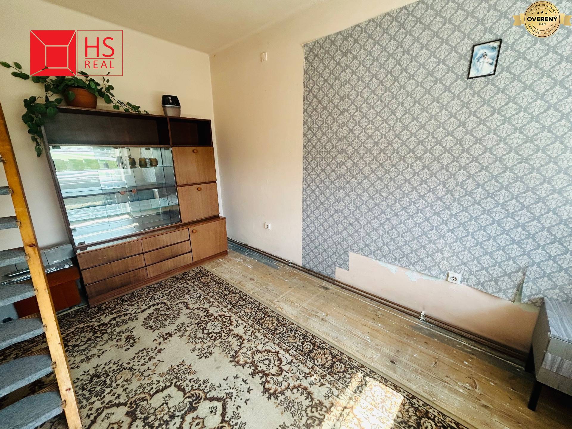 Izba s kobercom, starou komodou a podlahou s dreveným dekorom v rodinnom dome.