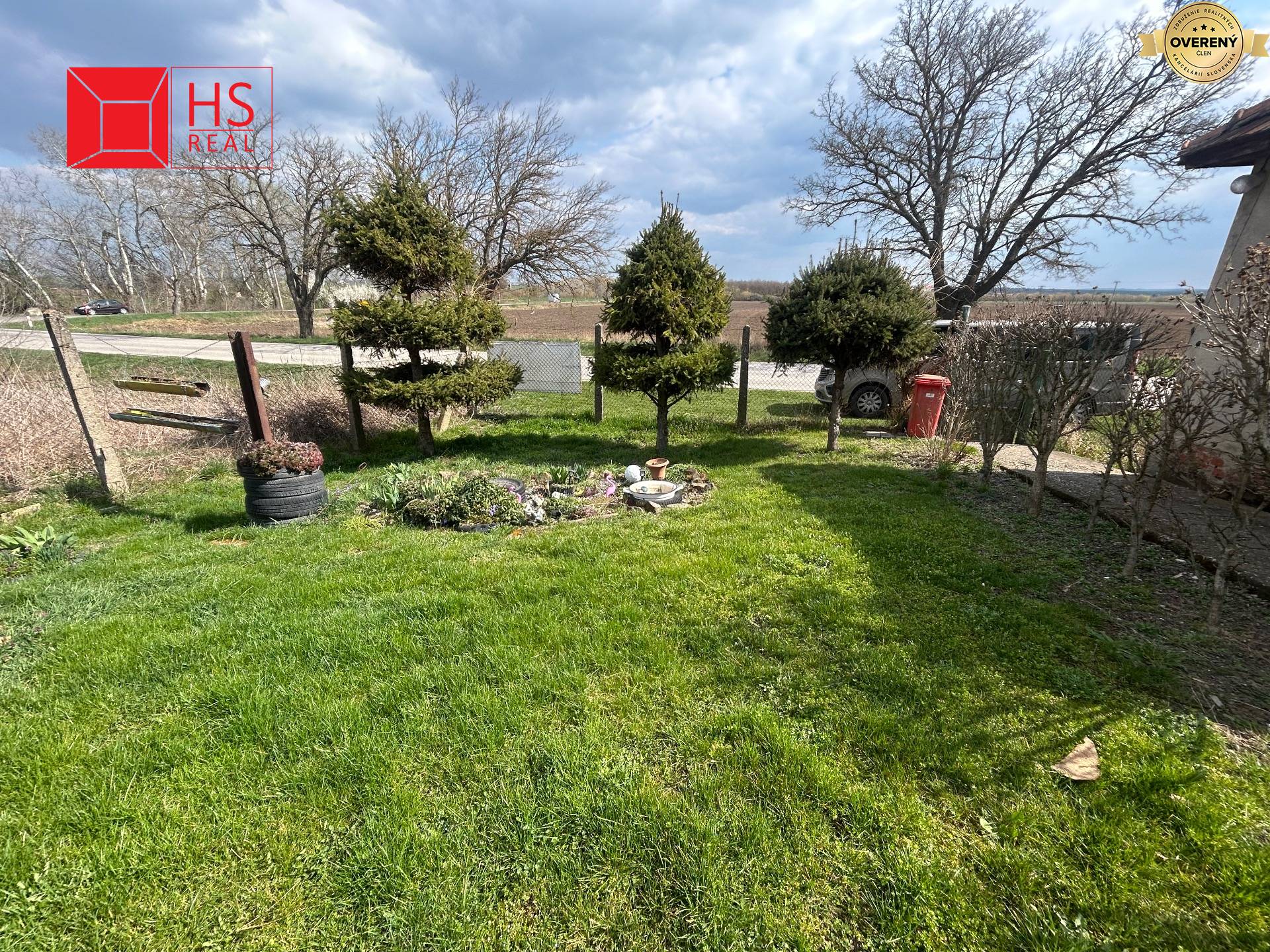 Záhrada rodinného domu na Veľkej Mani v Mani so stromami a kríkmi.