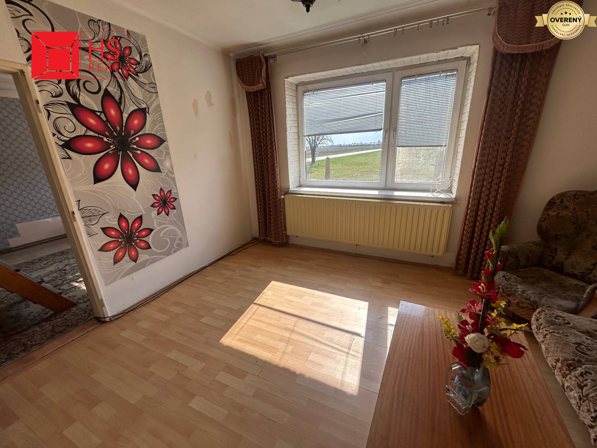 Izba v rodinnom dome s tapetou, podlahou s dreveným dekorom a kvetinovou výzdobou.