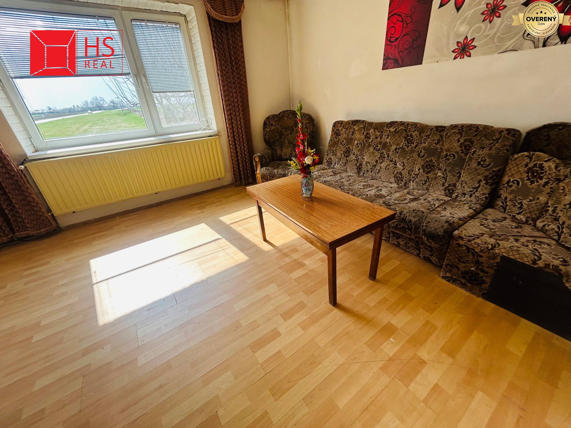 Obývacia izba v rodinnom dome s podlahou s dreveným dekorom a pohodlnou sedacou súpravou.